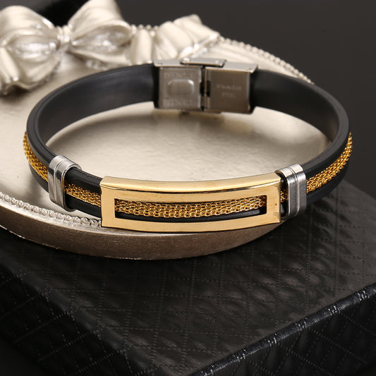 Black leather bracelet with gold and silver accents on a metallic surface