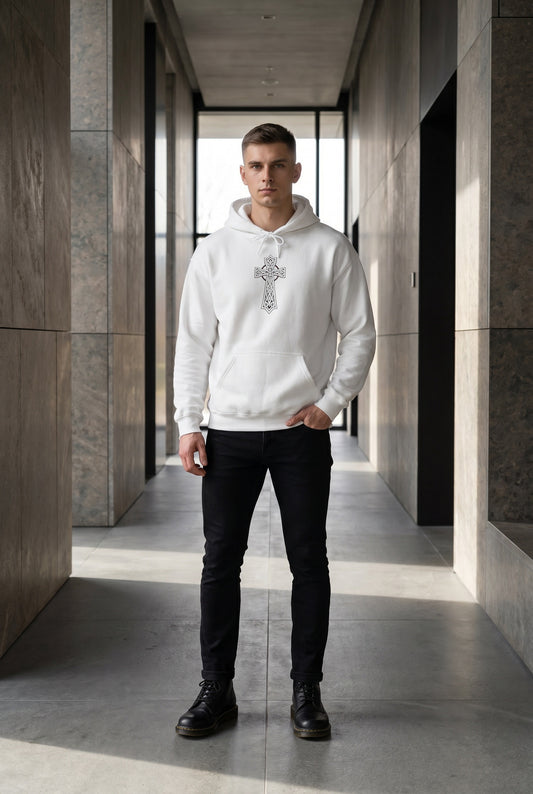 Man wearing a white hoodie with a cross design in a modern hallway.