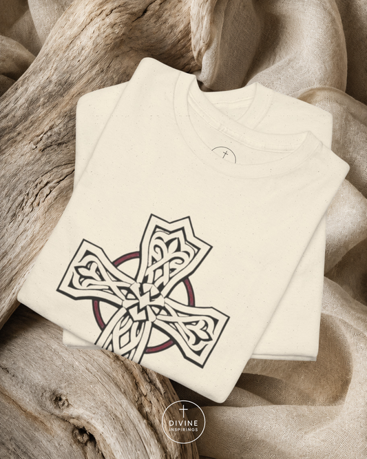 Folded t-shirt with a Celtic cross design on a natural wood and fabric background