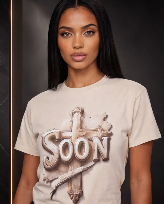 Woman wearing a beige t-shirt with 'SOON' graphic design on a dark background