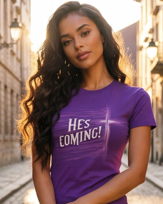 Woman wearing a purple t-shirt with 'HE'S COMING!' text on a city street.