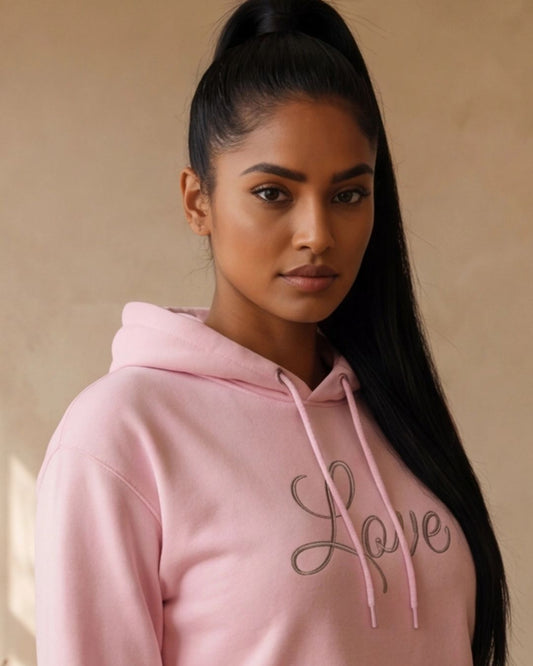Woman wearing a pink hoodie with 'Love' printed on it against a beige background