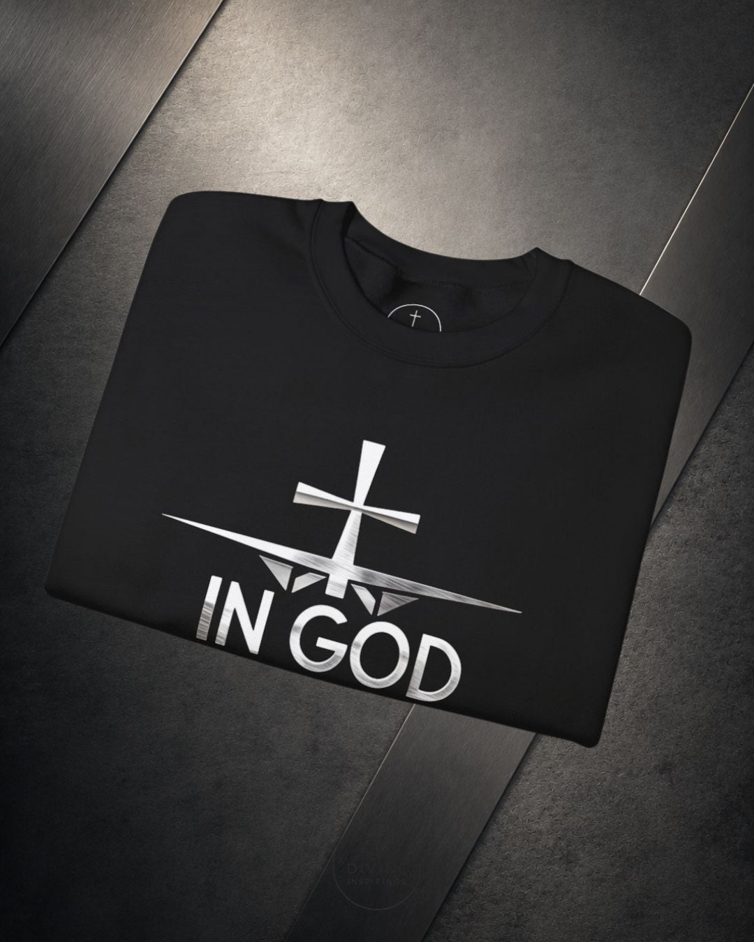 Black sweatshirt with 'IN GOD' text and cross design on a dark surface