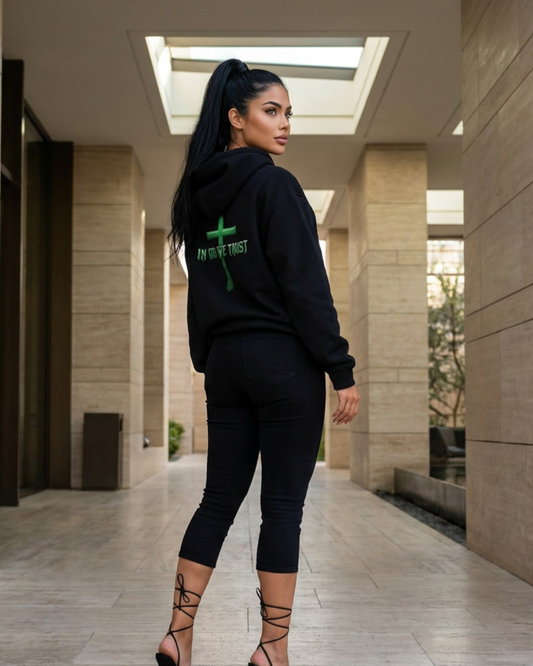 Woman wearing a black hoodie with a green logo and text, standing in a modern architectural setting.
