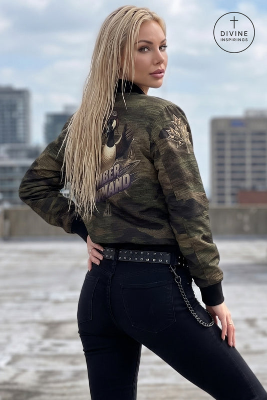 A blonde woman wearing a camouflage bomber jacket with a large graphic print on the back, styled with black jeans and a studded belt, posing outdoors with a city skyline in the background. A 'Divine INSPIRINGS' logo is visible in the top right corner.