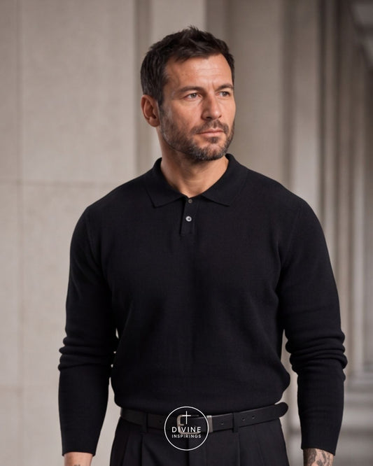 A man wearing a black long-sleeve polo shirt and dark trousers, standing against a light gray stone architectural background. A circular watermark logo for 'DIVINE INSPIRATION' is visible at the bottom center.