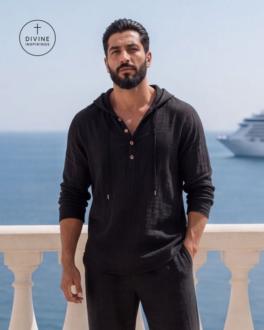 A man wearing a black long-sleeve hooded henley shirt and matching black pants stands on a balcony overlooking the ocean, with a cruise ship visible in the background. A Divine Inspirings logo is in the top-left corner.