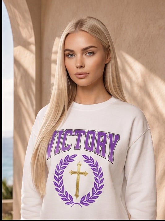 Woman wearing a white sweatshirt with 'VICTORY' and a cross design.