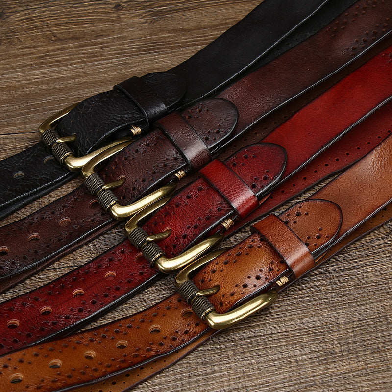 Four leather belts with brass buckles on a wooden surface