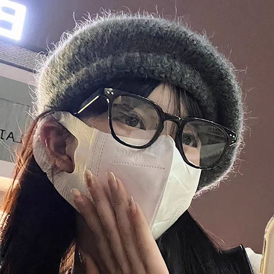 Person wearing a gray knit hat and black glasses with a white face mask.
