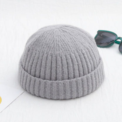 Gray knit beanie on a white background with sunglasses in the corner.