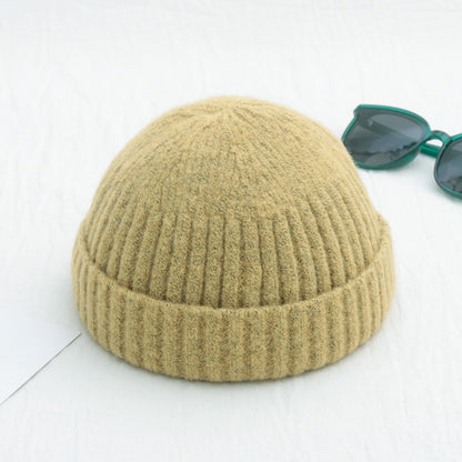 Beige knit beanie on a white background with green sunglasses to the side
