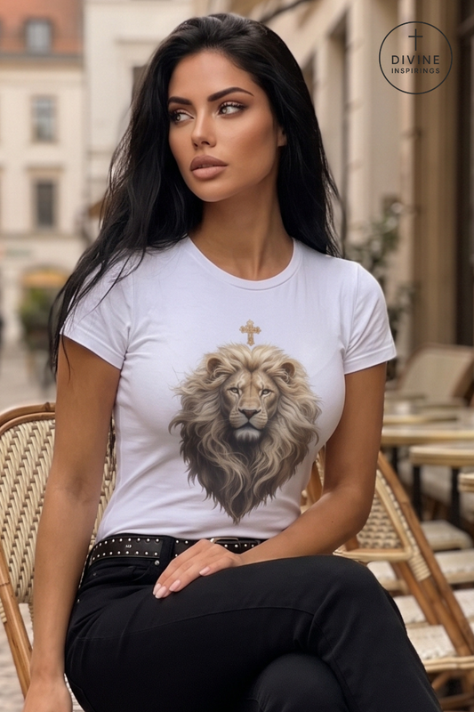 A woman sitting on a wicker chair wearing a white t-shirt with a detailed graphic of a lion's head and a small cross on the chest. The background shows a softly blurred outdoor cafe setting.