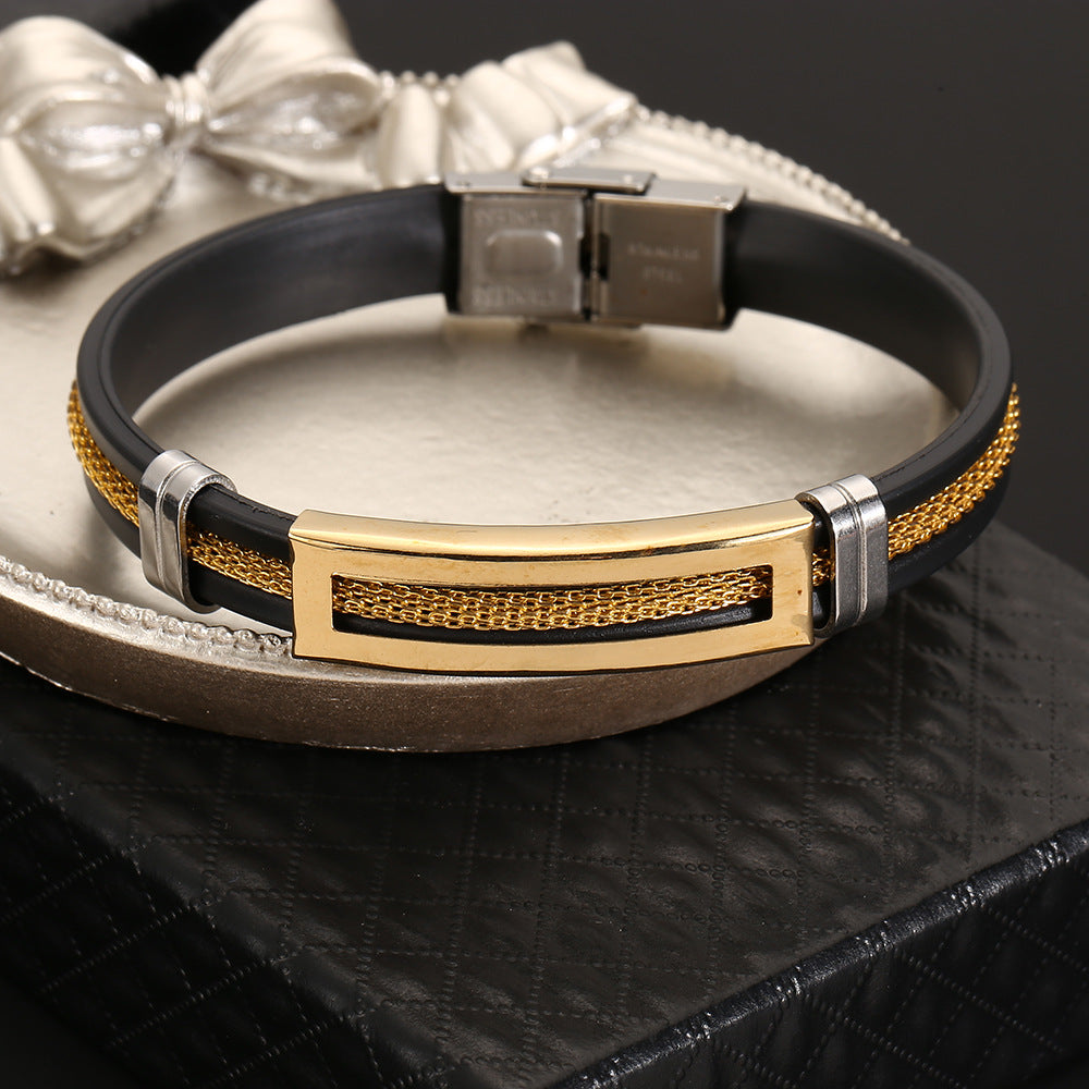 Black leather bracelet with gold and silver accents on a metallic surface