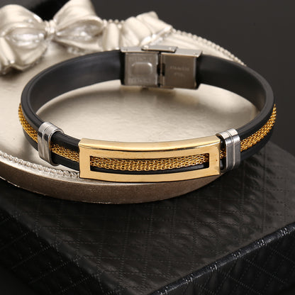 Black leather bracelet with gold and silver accents on a metallic surface