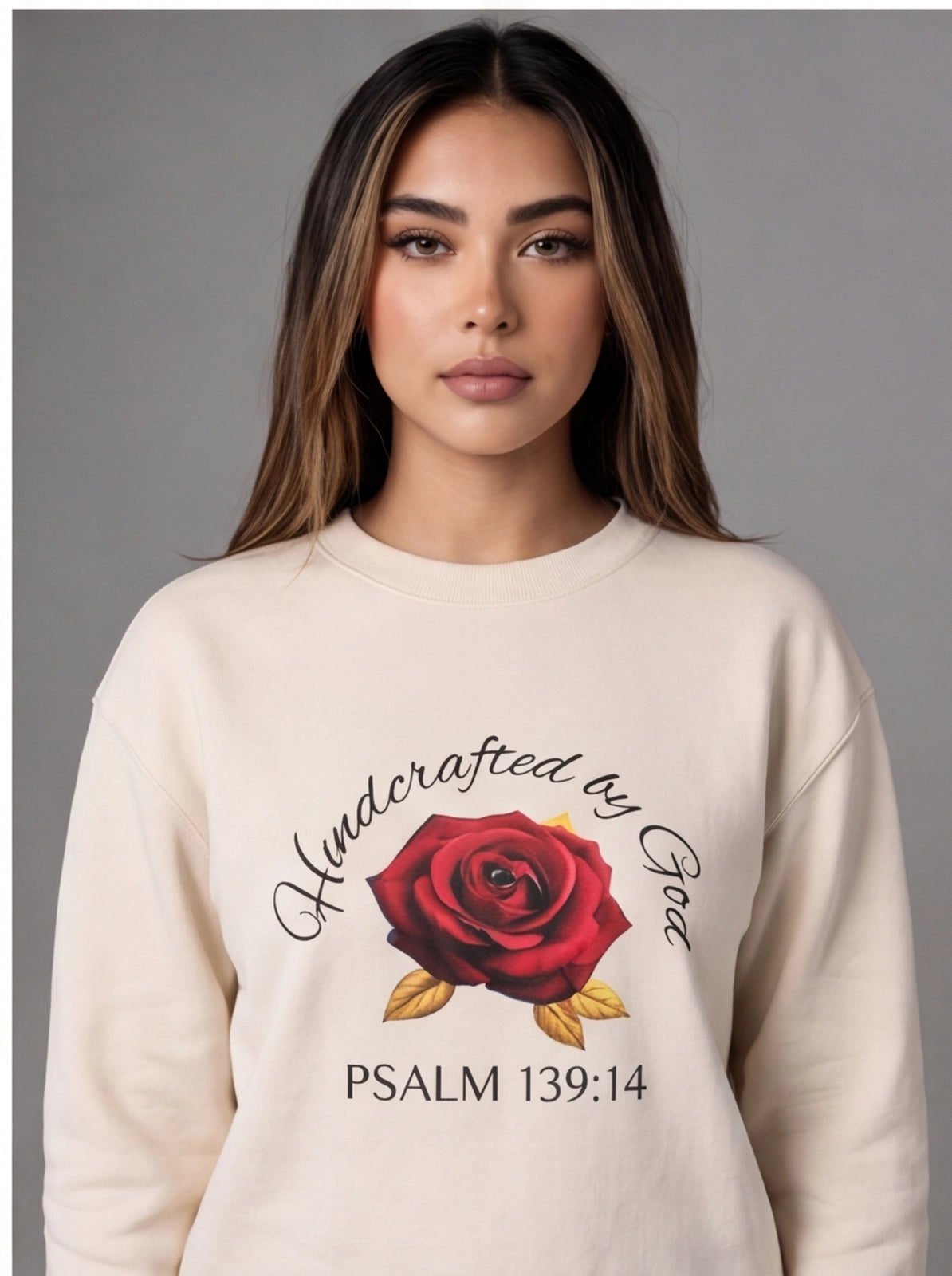 Woman wearing a cream sweatshirt with a red rose design and text on a gray background