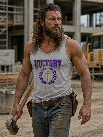 Man wearing a tank top with 'Victory' and a cross design, holding an axe in a construction site.