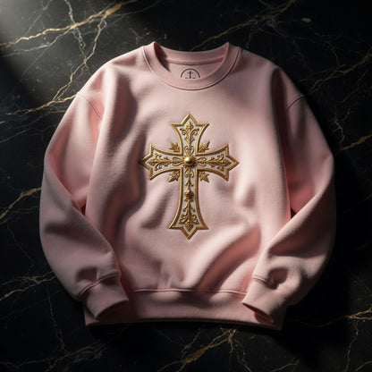 Pink sweatshirt with a gold cross design on a dark marble background