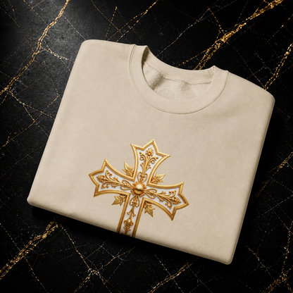 Folded beige sweatshirt with a gold embroidered cross on a dark background