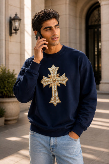 Man wearing a navy blue sweatshirt with a gold cross design, standing outdoors.