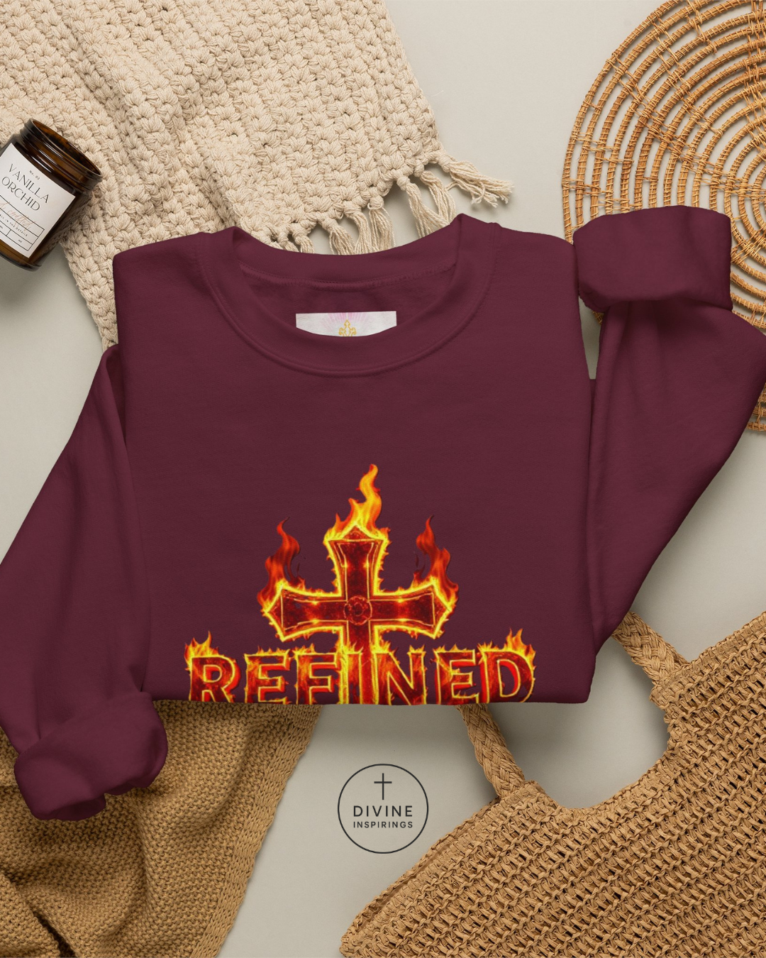 Maroon sweatshirt with 'REFINED' design featuring flames and a cross on a textured surface.