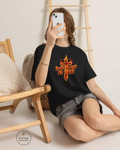 Person wearing a black t-shirt with 'Risen in Fire' design, sitting on the floor with a wooden chair and ladder in the background.