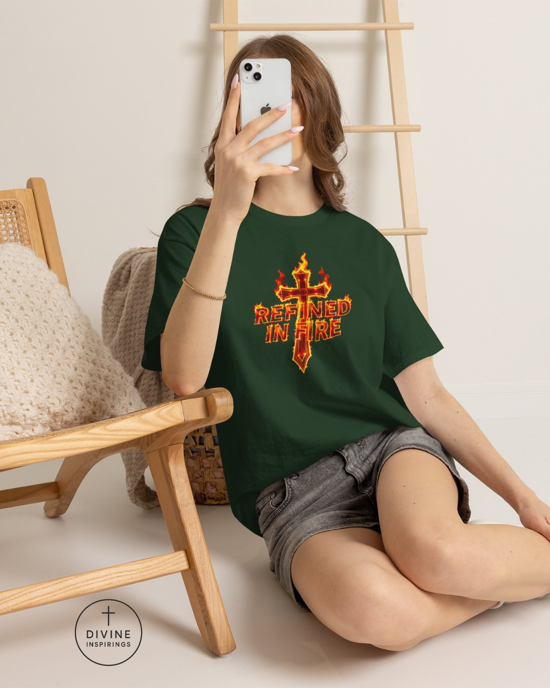 Person wearing a green t-shirt with a graphic design, sitting on the floor with a wooden chair and ladder in the background.