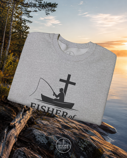 Gray sweatshirt with a fishing graphic and 'Fisher of Men' text on a rock by a lake with sunset.