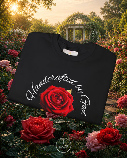 Black sweatshirt with a red rose and 'Handcrafted by God' text in a garden setting