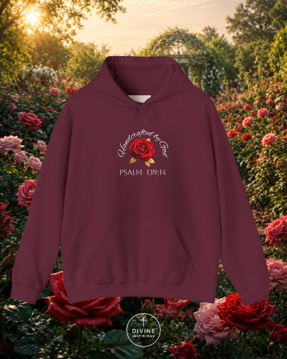 Maroon hoodie with a rose design and text in a garden setting