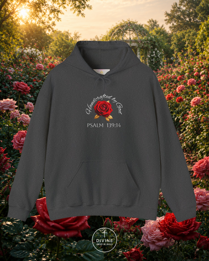 Dark gray hoodie with a red rose design and text, set against a garden background.