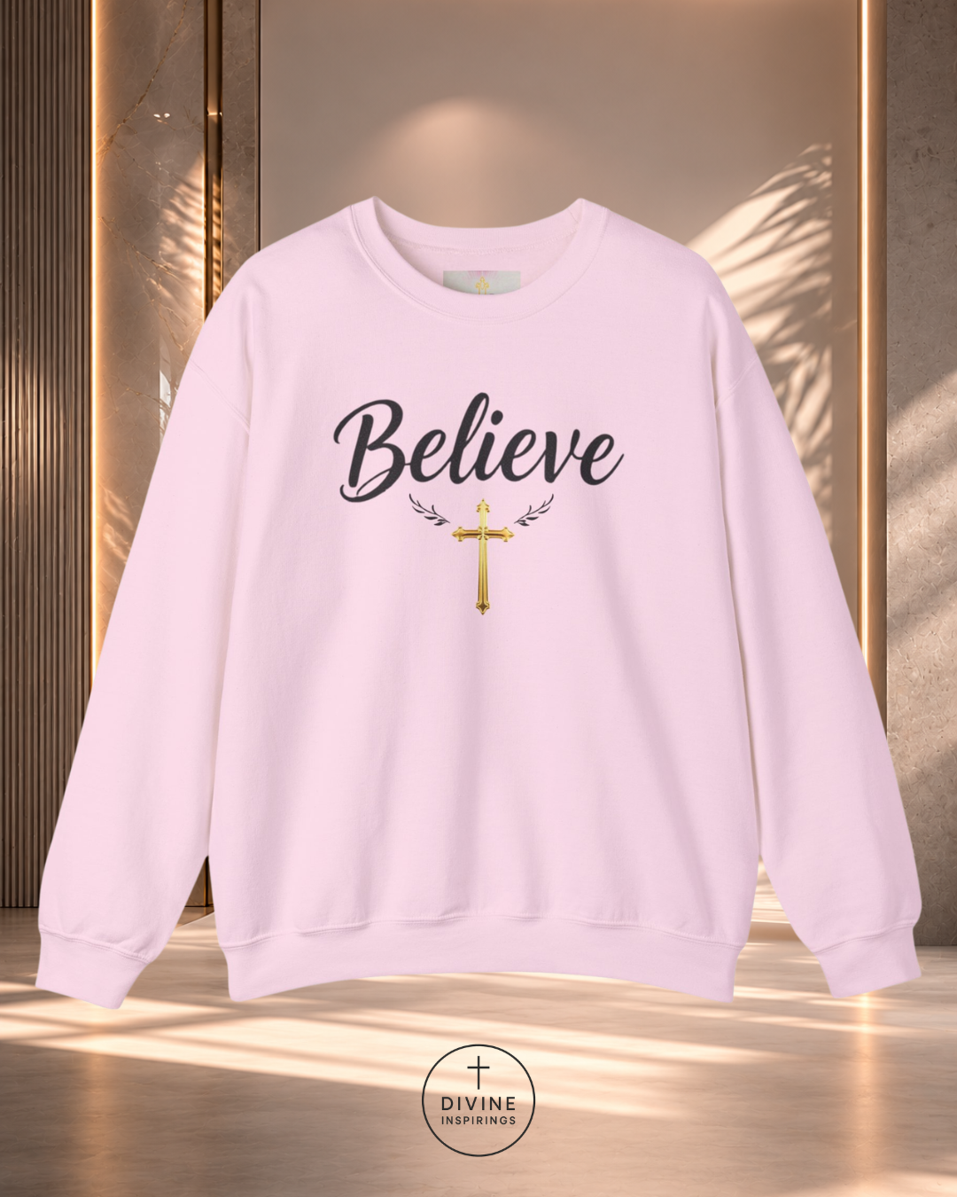 Light purple sweatshirt with 'Believe' text and cross design on a reflective surface.