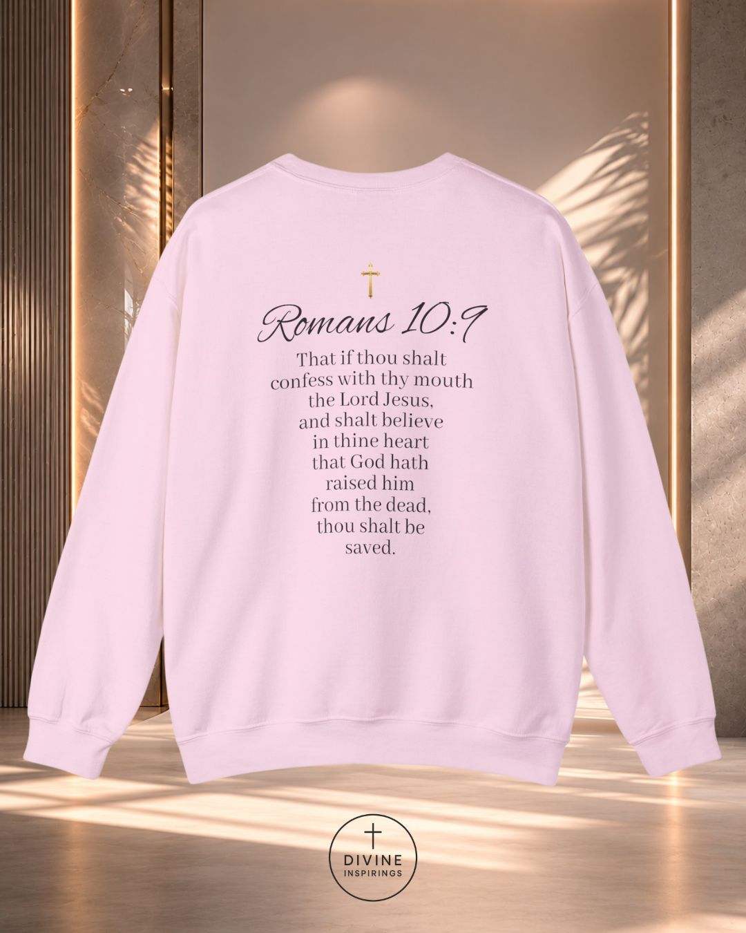 Light pink sweatshirt with text and a cross on a reflective surface