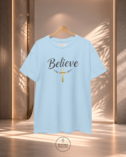 Light blue t-shirt with 'Believe' and cross design on a hanger against a neutral background