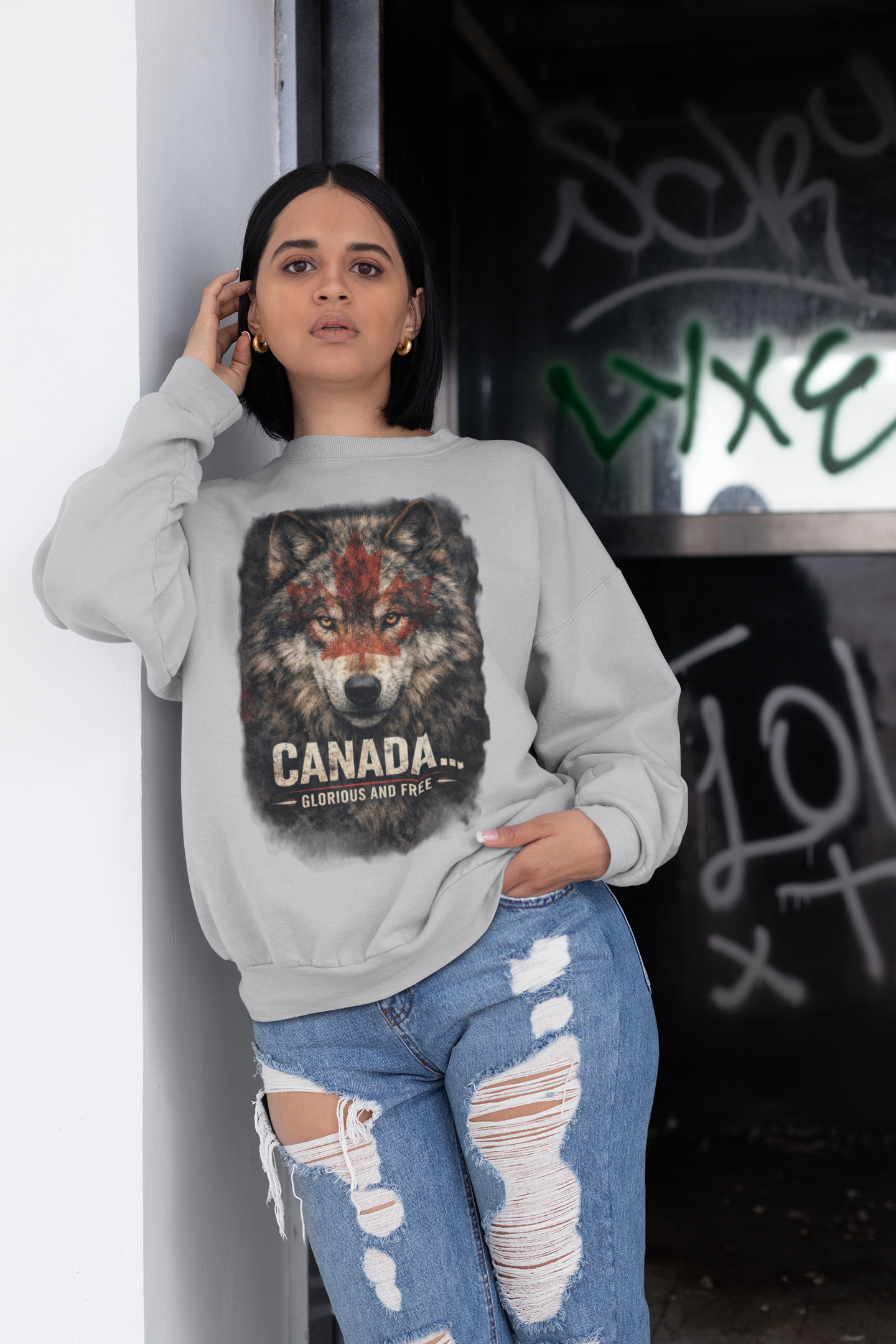 Person wearing a gray sweatshirt with a wolf graphic and 'Canada' text, standing against a graffiti-covered wall.
