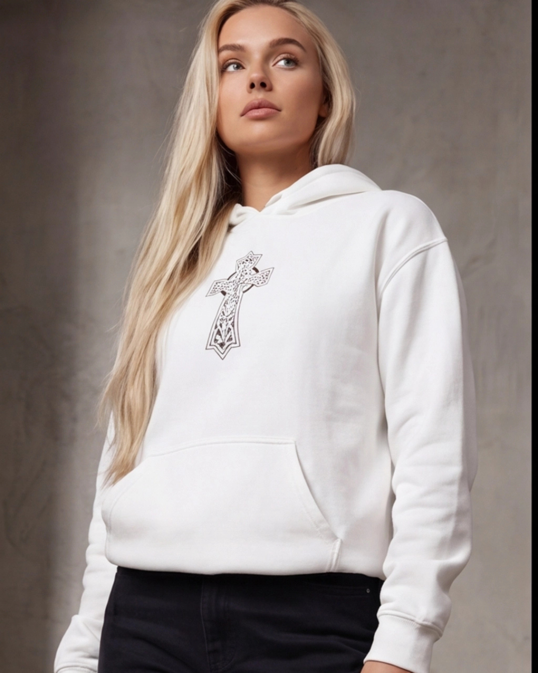 Woman wearing a white hoodie with a decorative cross design on a neutral background