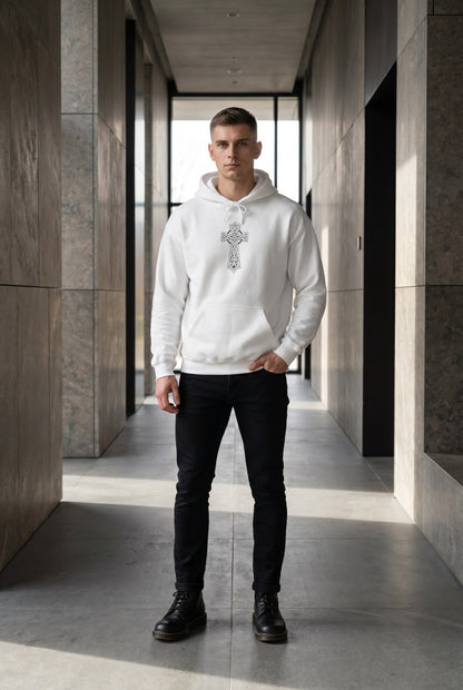 Man wearing a white hoodie with a cross design in a modern hallway.