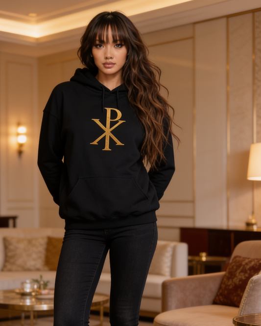 Woman wearing a black hoodie with a gold logo in an elegant room.