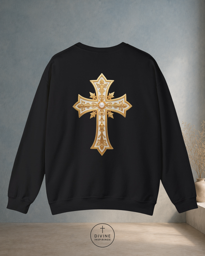 Black sweatshirt with a gold cross design on the back against a gray wall.