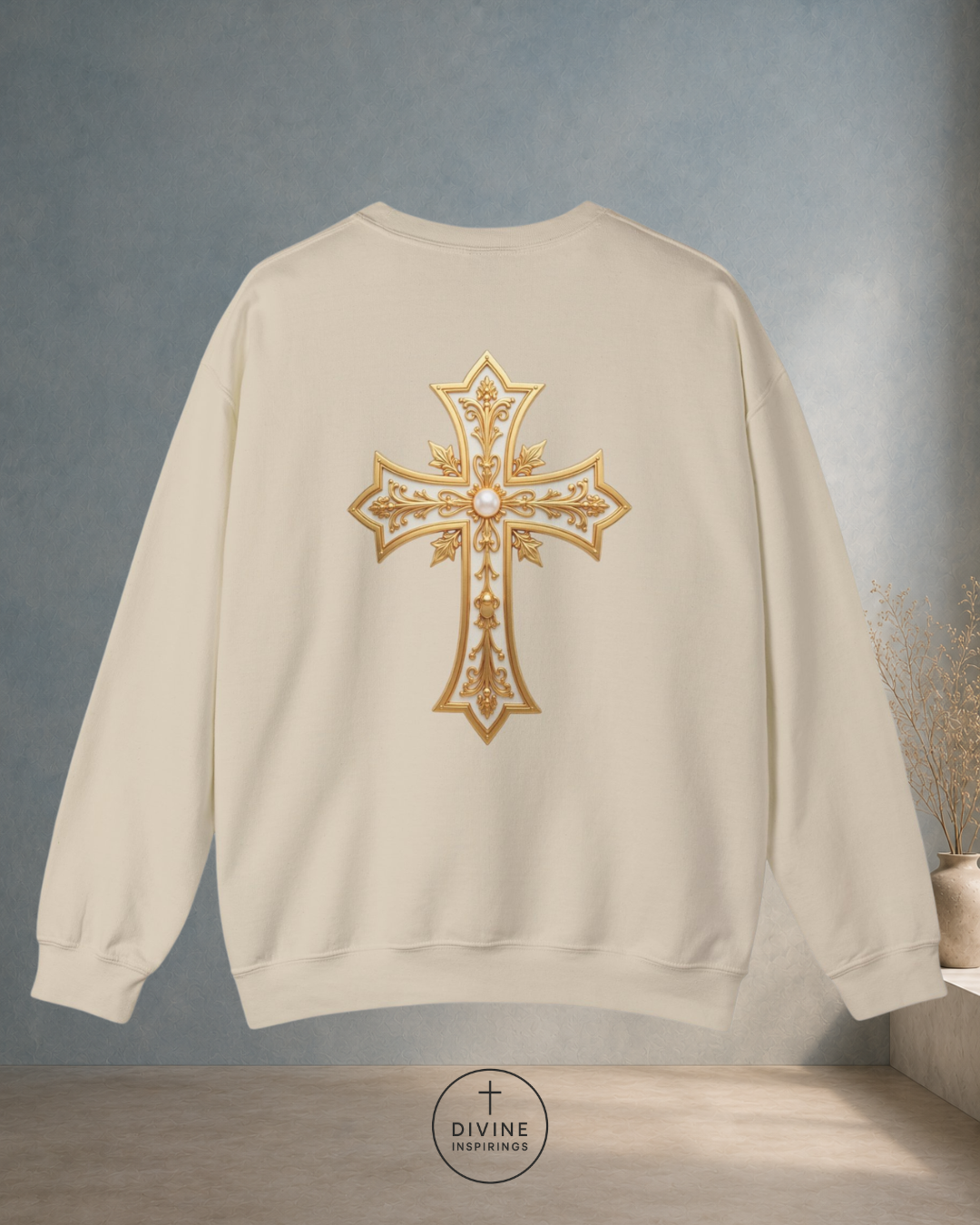 Beige sweatshirt with a gold cross design on the back against a gray background.
