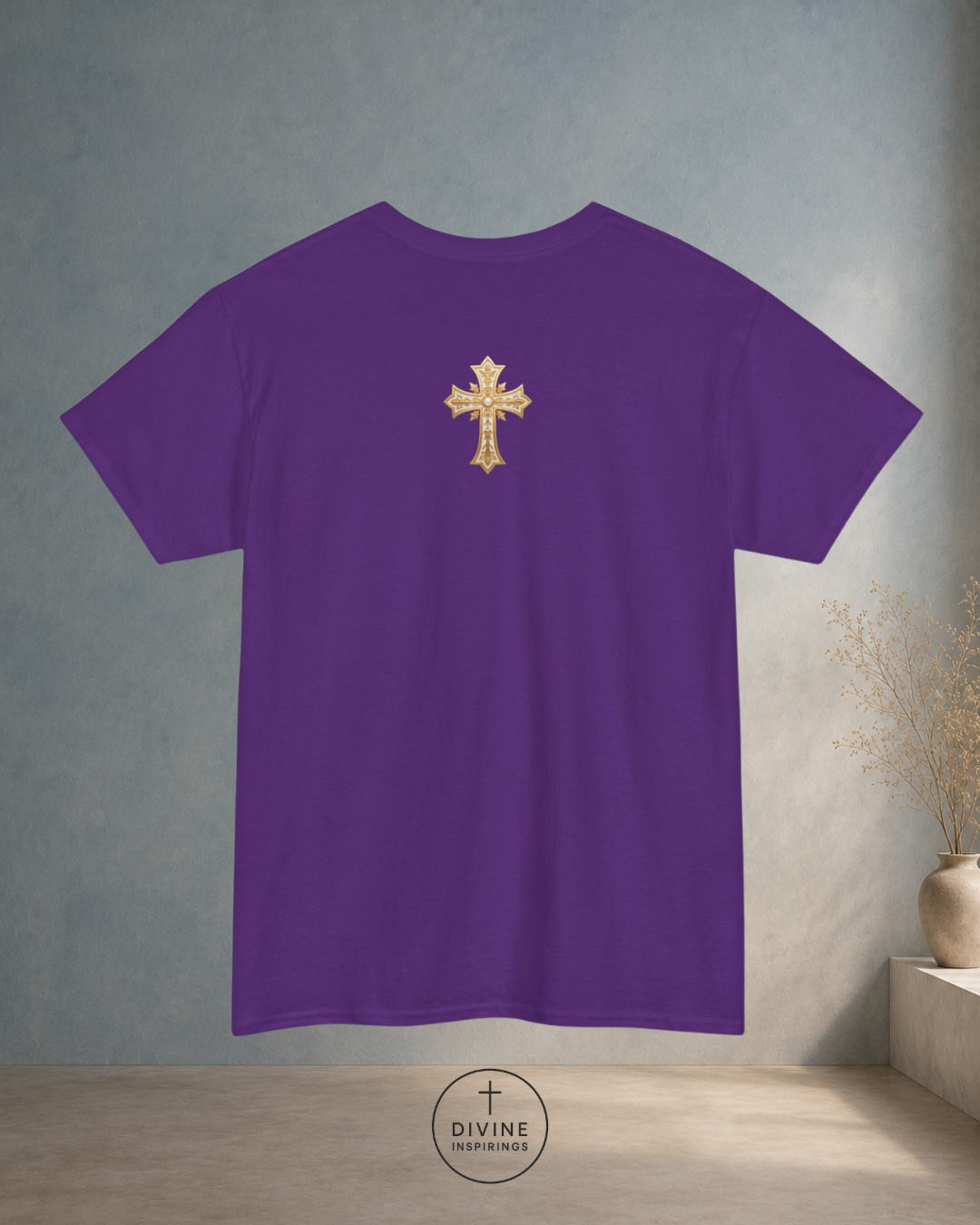 Purple t-shirt with a gold cross on the back, displayed against a neutral wall.