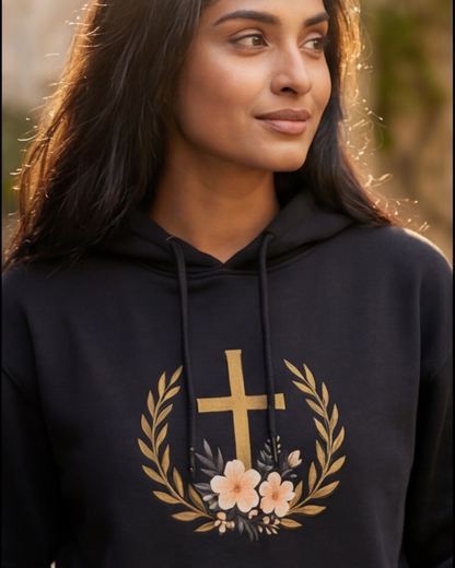 Person wearing a black hoodie with a gold cross and floral design.