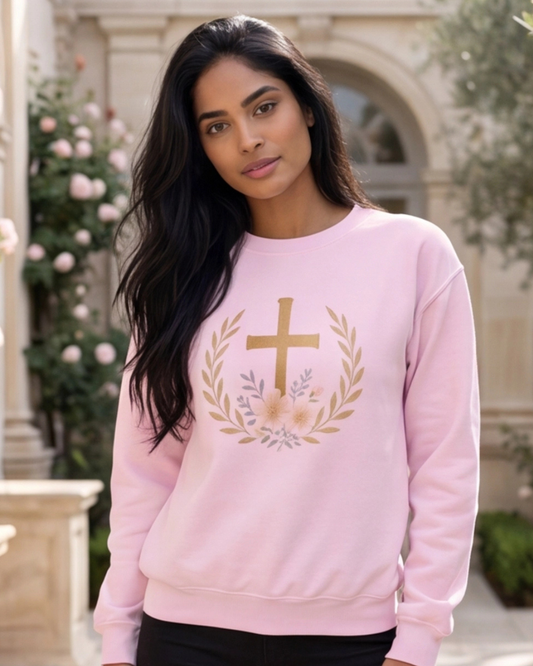 Woman wearing a pink sweatshirt with a cross and floral design outdoors.