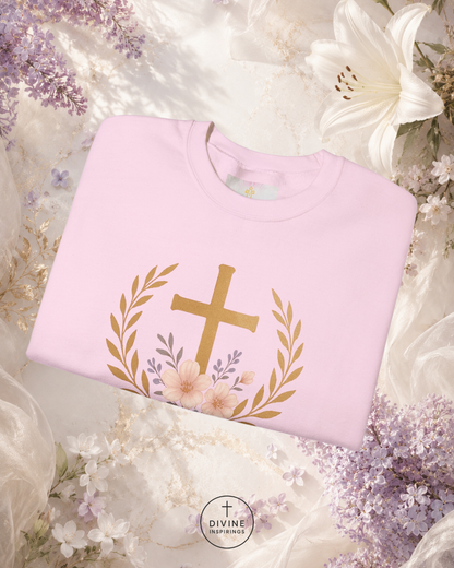 Pink sweatshirt with gold cross design on a floral background