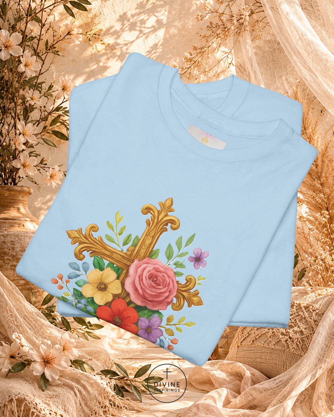 Light blue sweatshirt with floral and cross design on a textured beige background
