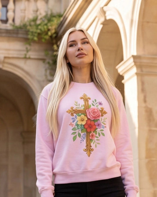 Woman wearing a pink sweatshirt with a floral cross design outdoors.