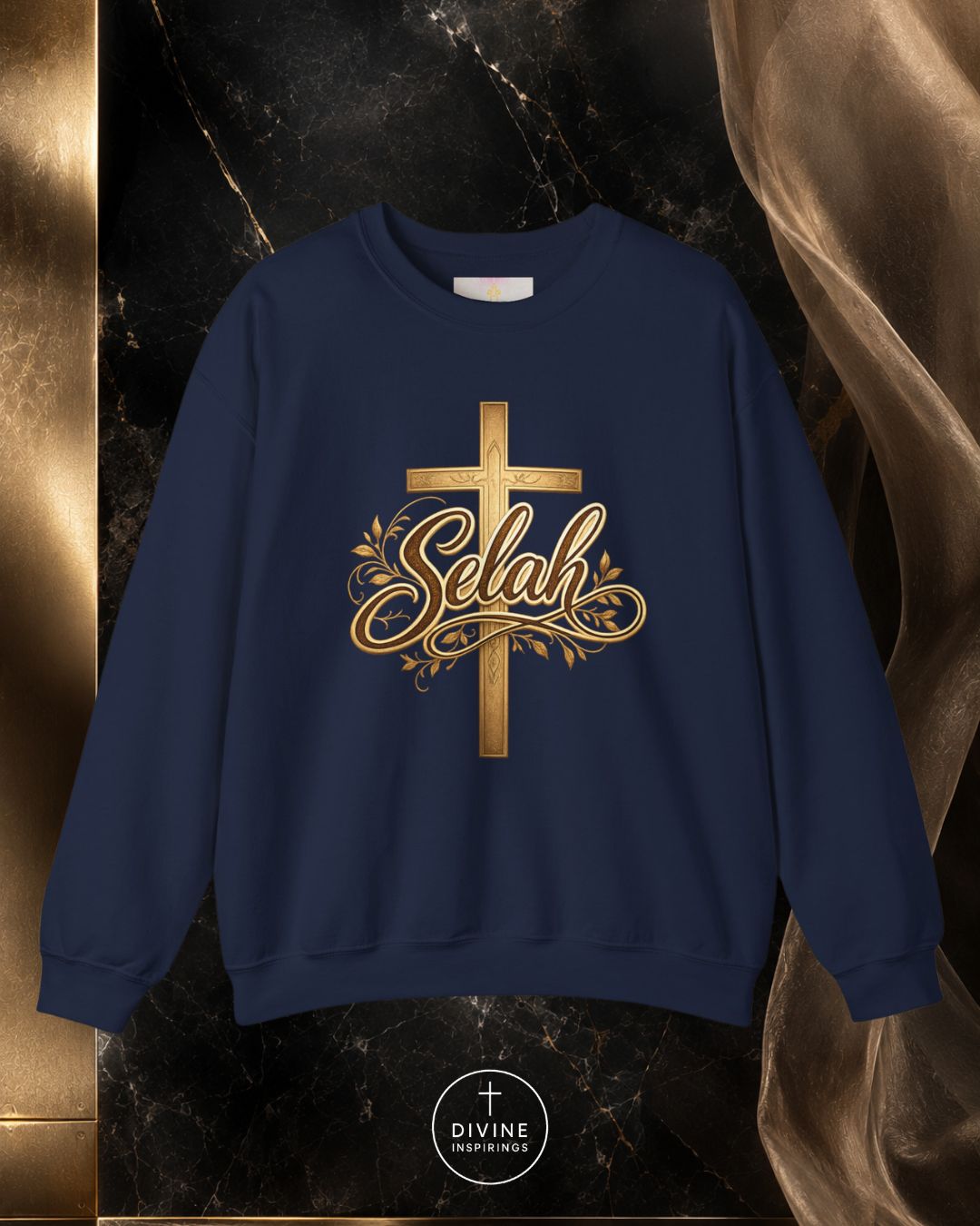 Navy blue sweatshirt with gold cross and 'Selah' text on a dark marble background