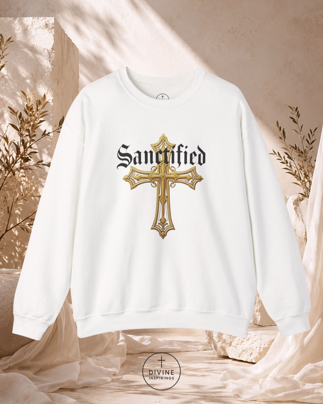 White sweatshirt with gold cross design and 'Sanctified' text on a neutral background