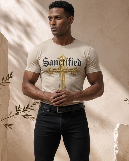 Man wearing a white t-shirt with 'Sanctified' and a cross design, standing against a textured beige wall.