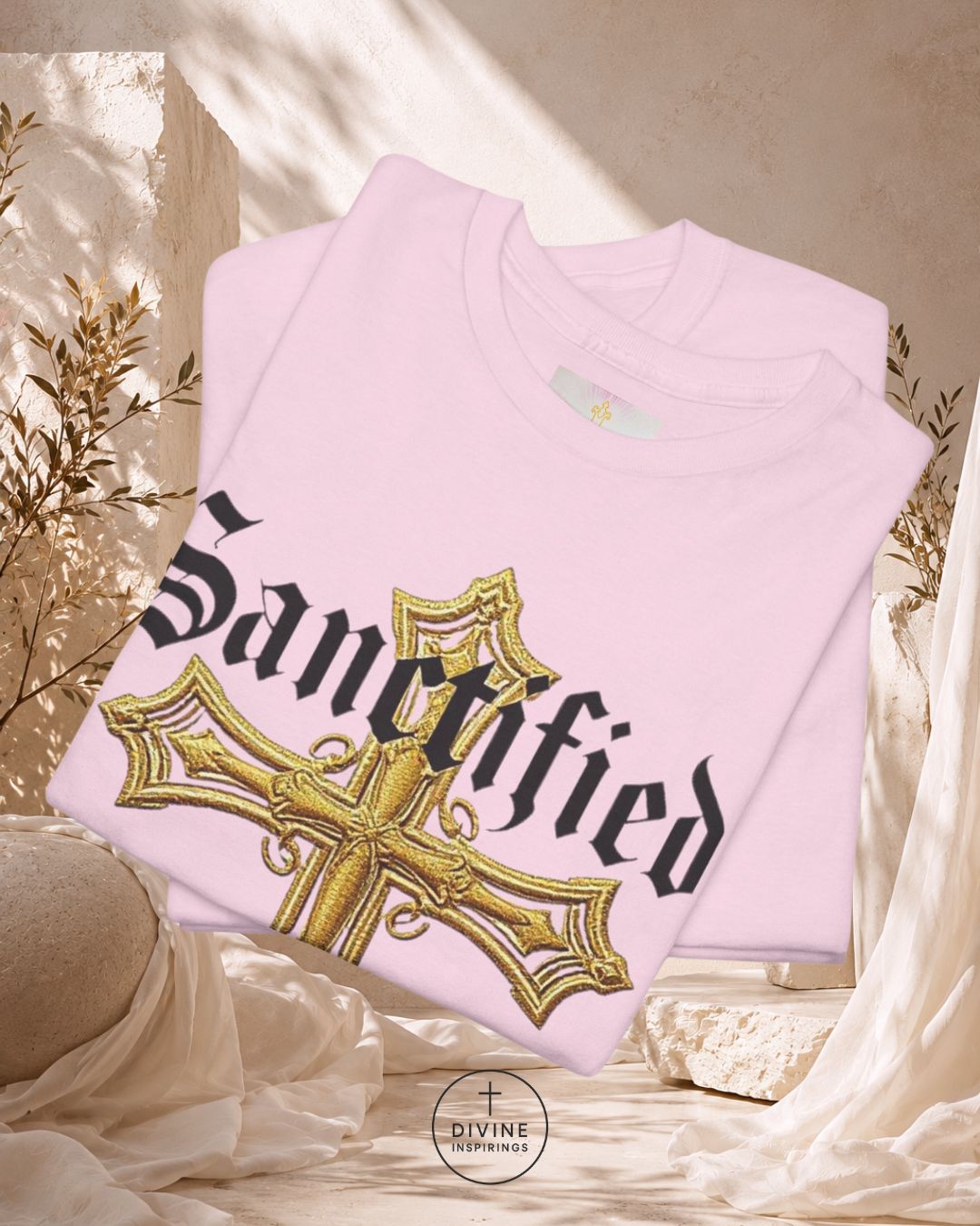 Pink sweatshirt with gold cross and 'Sanctified' text on a neutral background